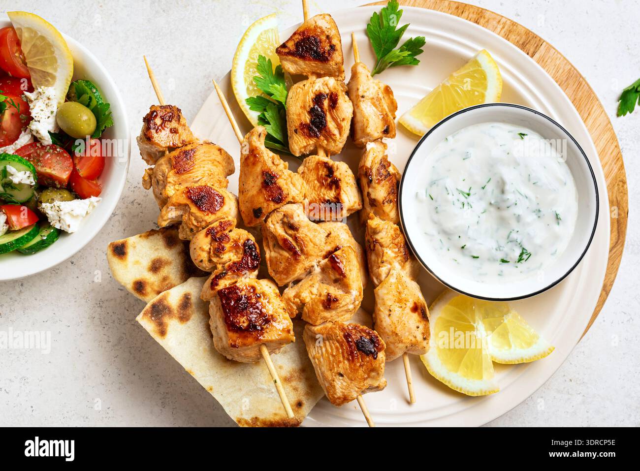 Spiedini di souvlaki alla griglia, insalata greca e tzatziki Foto Stock