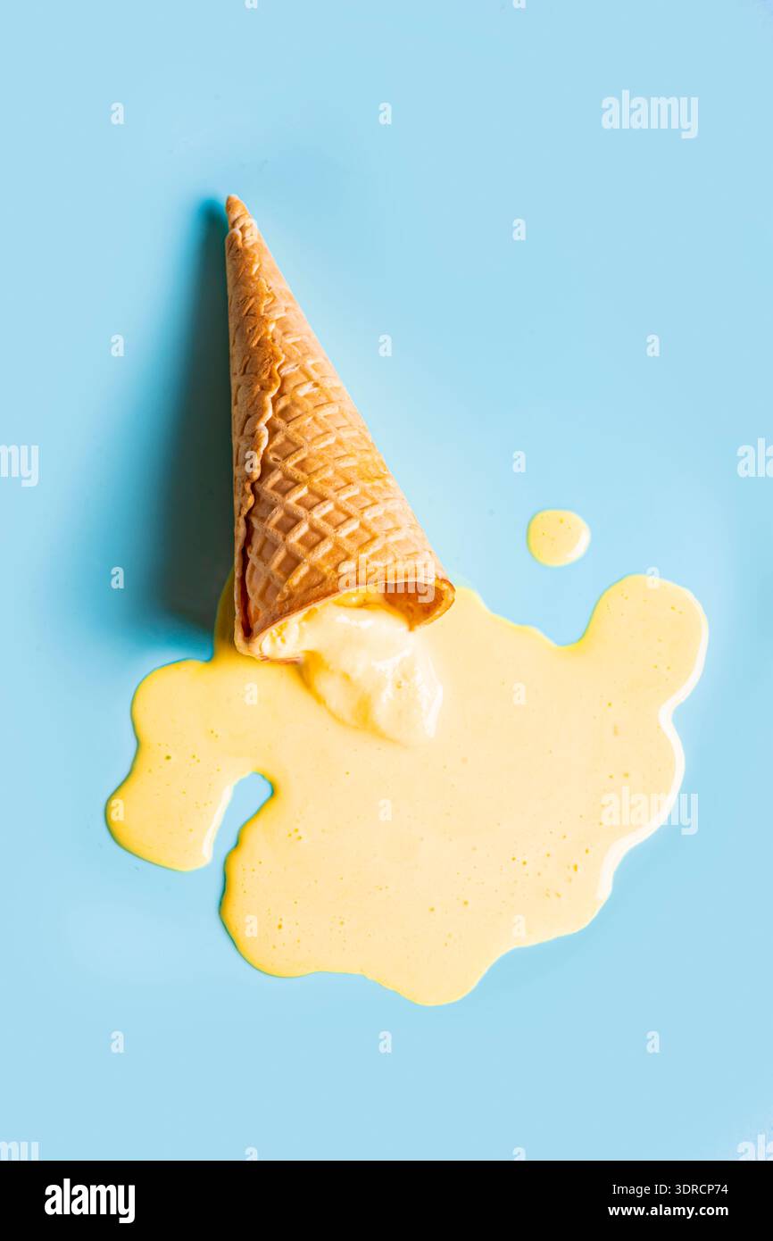 Cono per waffle con gelato giallo fuso Foto Stock