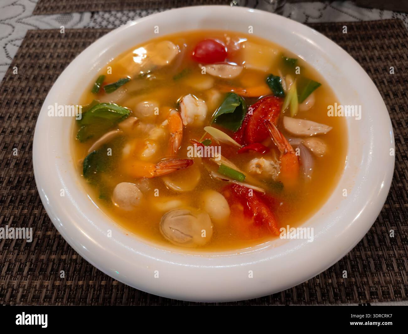 Primo piano di una ciotola di zuppa piccante di tom yum tailandese con erbe, peperoncino e gamberi, con sapori vivaci e cucina tradizionale. Perfetto per il cibo, res Foto Stock
