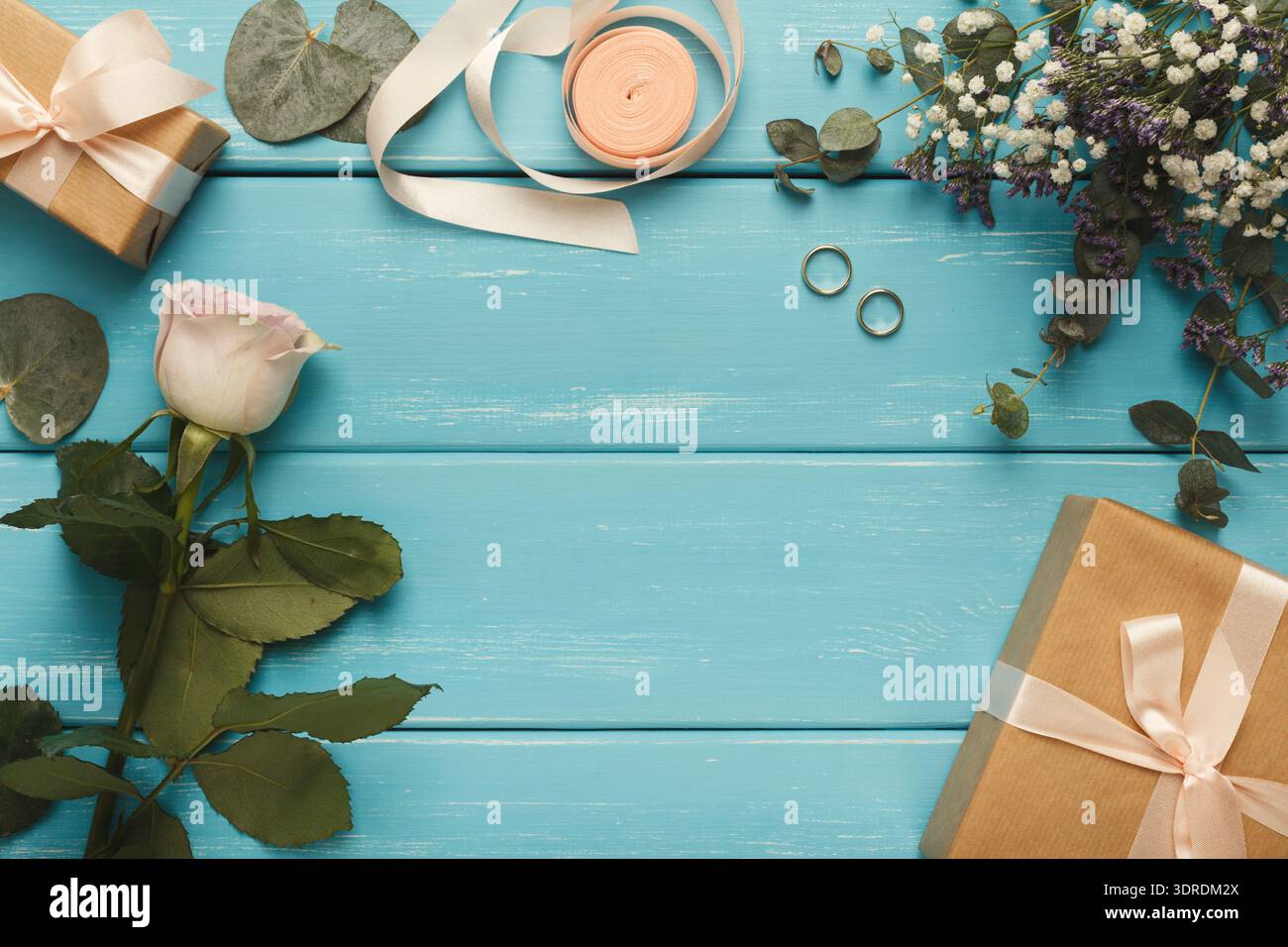 Collage di articoli da regalo con fiori e anelli su una superficie in legno blu Foto Stock
