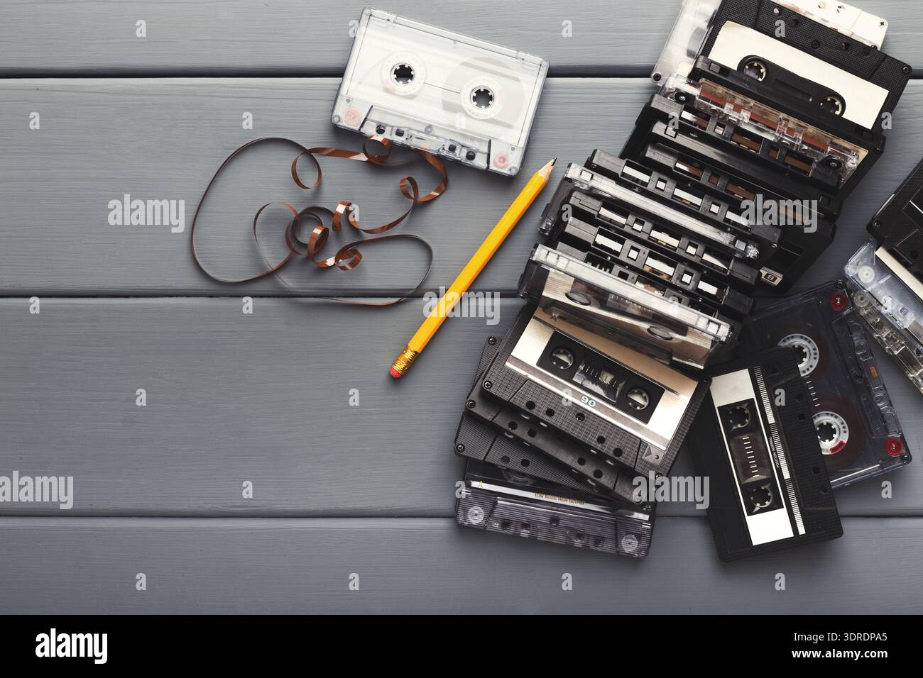 Raccolta di vecchie cassette audio disposte su un tavolo accanto a una matita e a un nastro Foto Stock