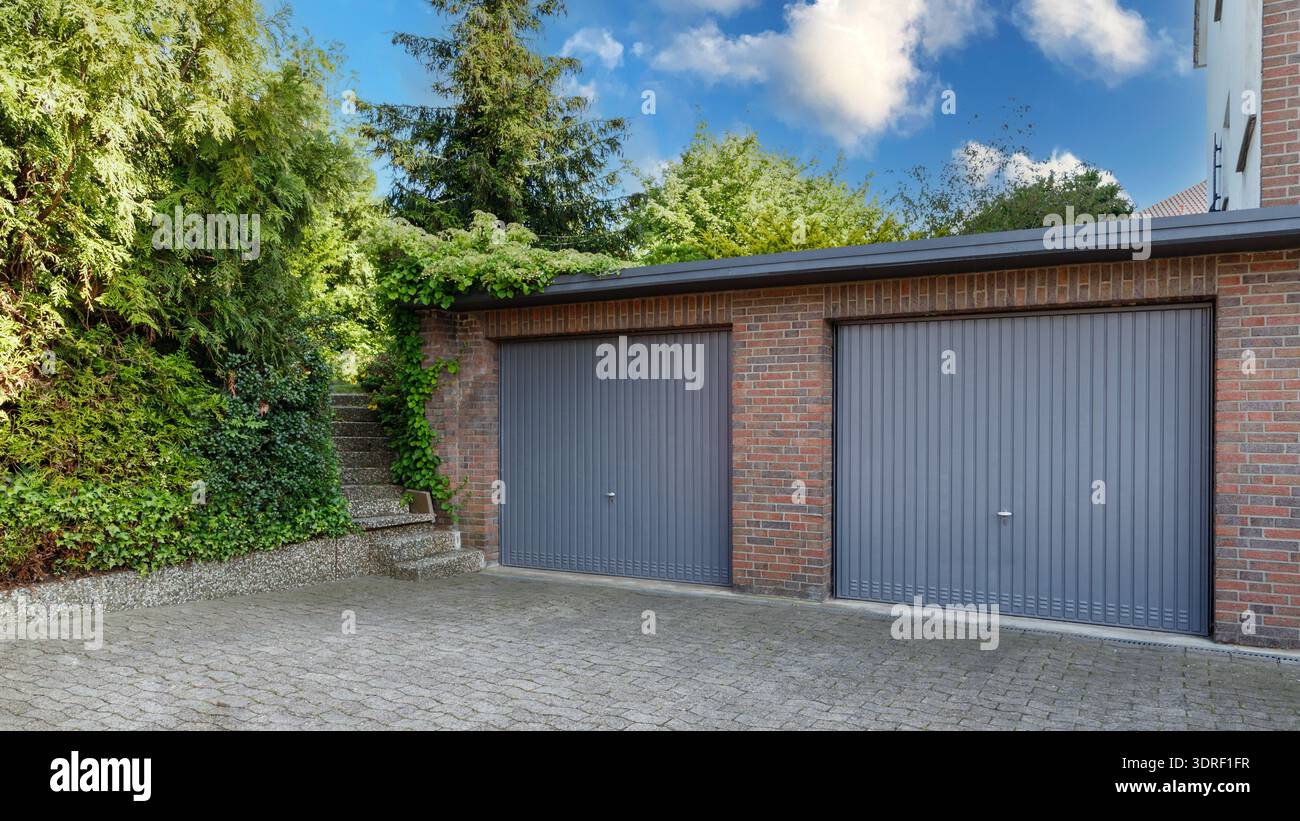 Moderno parcheggio in una casa residenziale in mattoni per auto con persiane grigie sui cancelli. Porte chiuse nei garage. Foto Stock