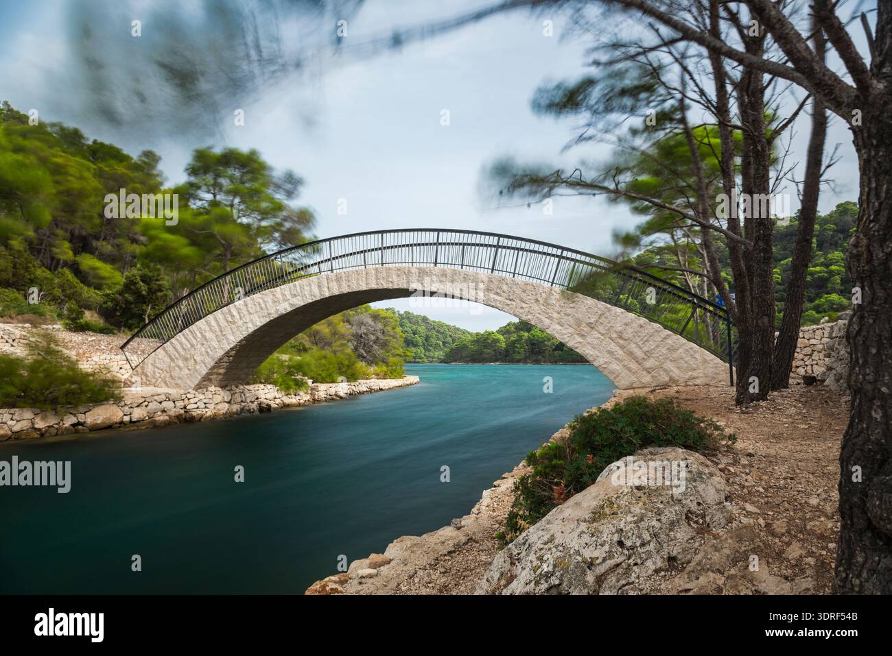 Il ponte ad arco in pietra sul canale Solinski tra il mare aperto e il grande lago sull'isola di Mljet in tempesta Foto Stock