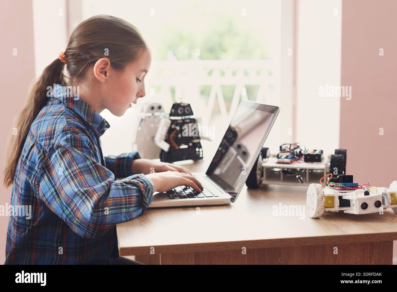 Un bambino lavora su un computer portatile con robot in un ambiente in classe durante una sessione tecnica Foto Stock