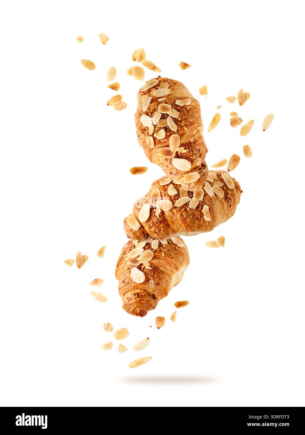 Croissant alle mandorle appena sfornati con briciole di noci che volano isolate su sfondo bianco. Tre croissant cadono. Scheda pasticceria. Foto Stock