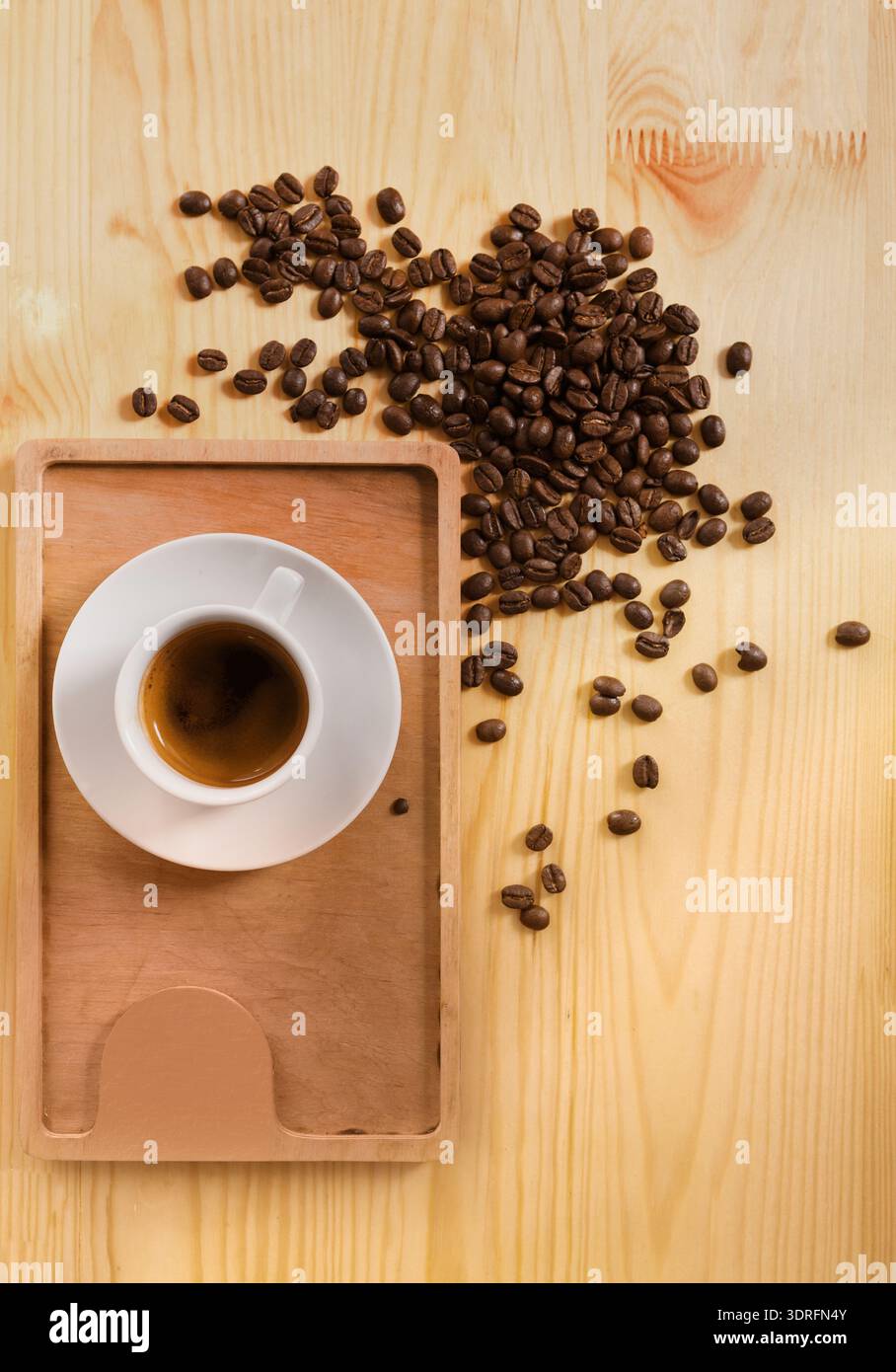 Tazza da caffè su una superficie in legno circondata da chicchi di caffè versati in un'esposizione della collezione Foto Stock