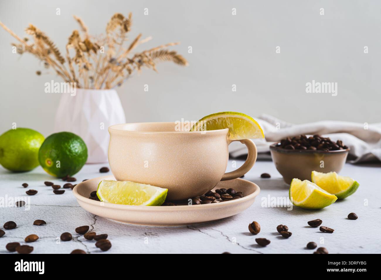 Caffè freddo con spicchi di lime in una tazza sul tavolo Foto Stock