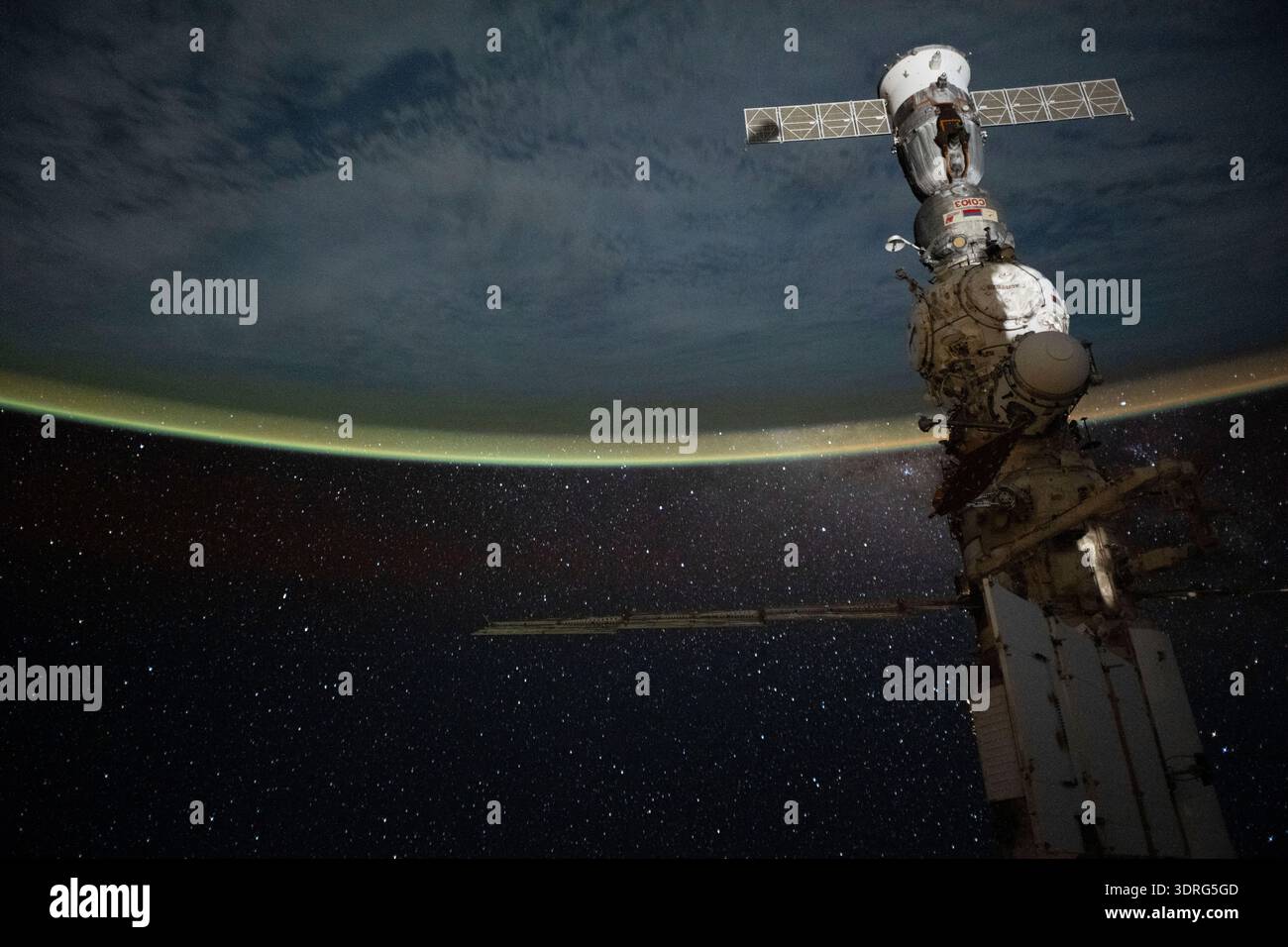 Un soffio giallo-verde copre l'orizzonte della Terra sotto un cielo pieno di stelle in questa foto a lunga esposizione scattata dalla stazione spaziale Internazionale mentre orbitava a 265 km sopra il nuvoloso Oceano Pacifico al largo della costa del Cile. In primo piano, la navicella Soyuz MS-27 è ancorata al modulo Prichal, che è a sua volta collegato al modulo scientifico Nauka. Una fotografia scattata dalla stazione spaziale Internazionale il 13 ottobre 2025. Una versione ottimizzata di un'immagine originale della NASA: Credit NASA/ZCardman Foto Stock