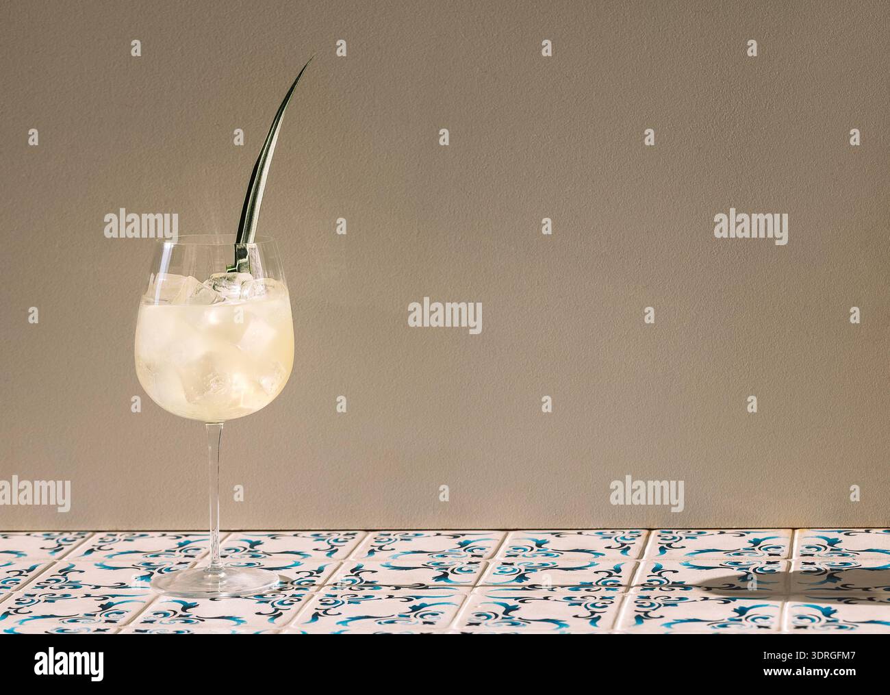 Un elegante bicchiere con spritz scintillante e una foglia verde Foto Stock