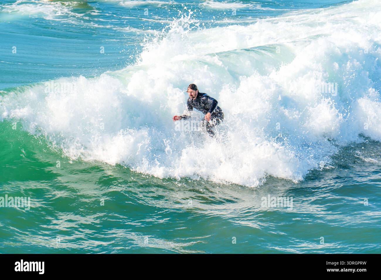 Oceanside, California - 28 dicembre 2025: Oceanside, la dinamica onda oceanica della California, è guidata attivamente da un surfista maschio in muta su un luminoso, su Foto Stock