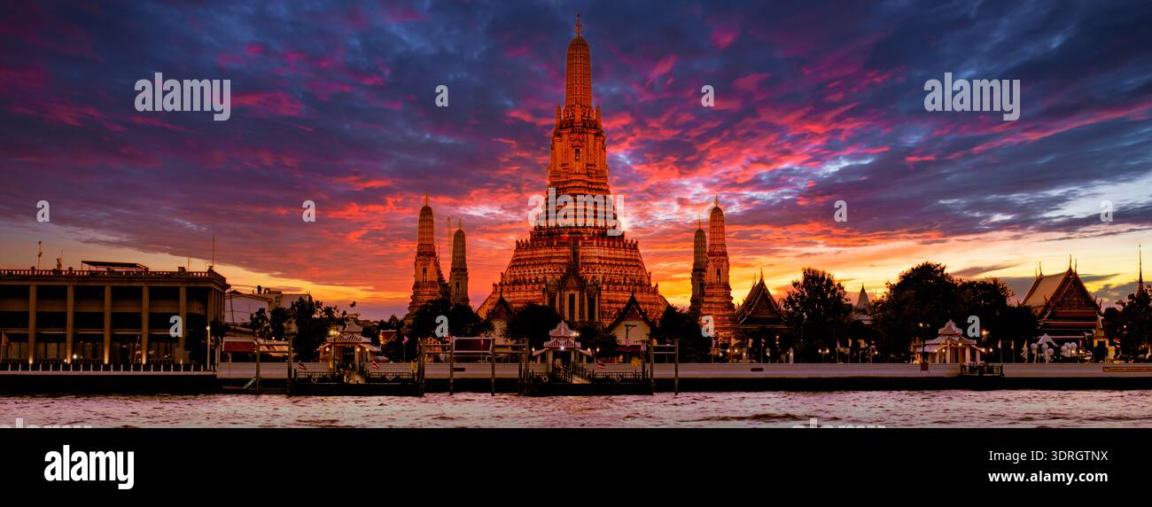 I templi dorati si immergono nelle sfumature del tramonto lungo il fiume Chao Phraya a Bangkok in Thailandia Foto Stock