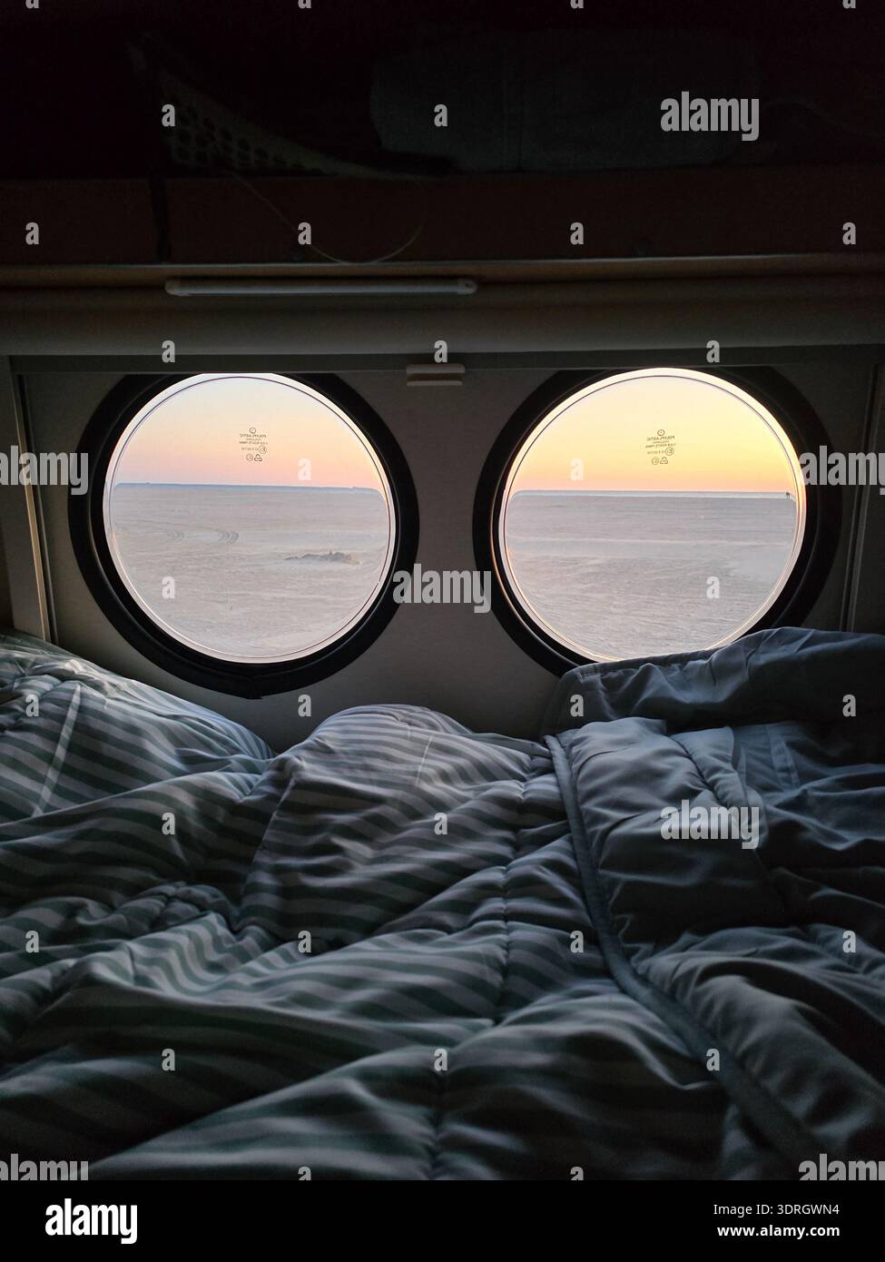 Accogliente vista da un letto con finestre circolari che si affacciano su una tranquilla alba in Danimarca Foto Stock