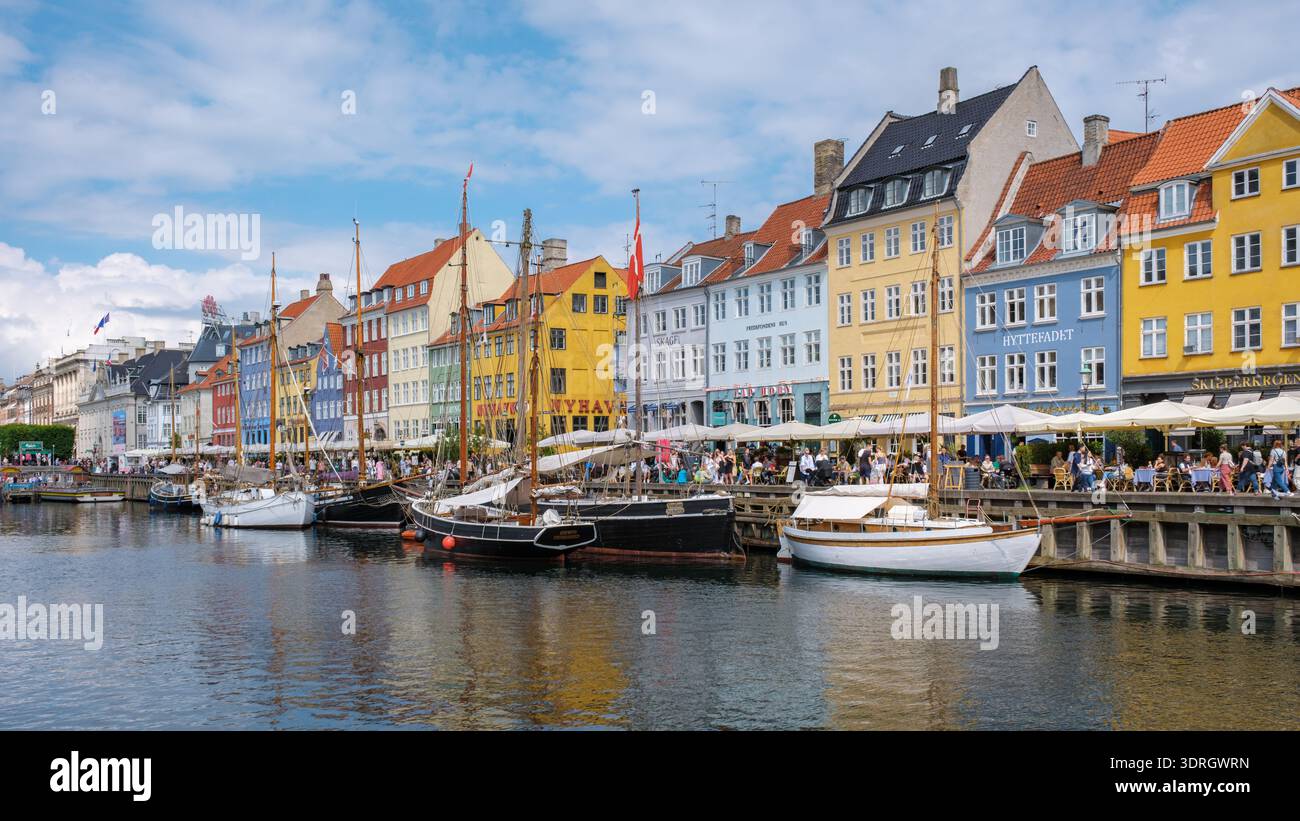 Esplora il vivace lungomare di Nyhavn a Copenaghen con edifici colorati e barche Foto Stock