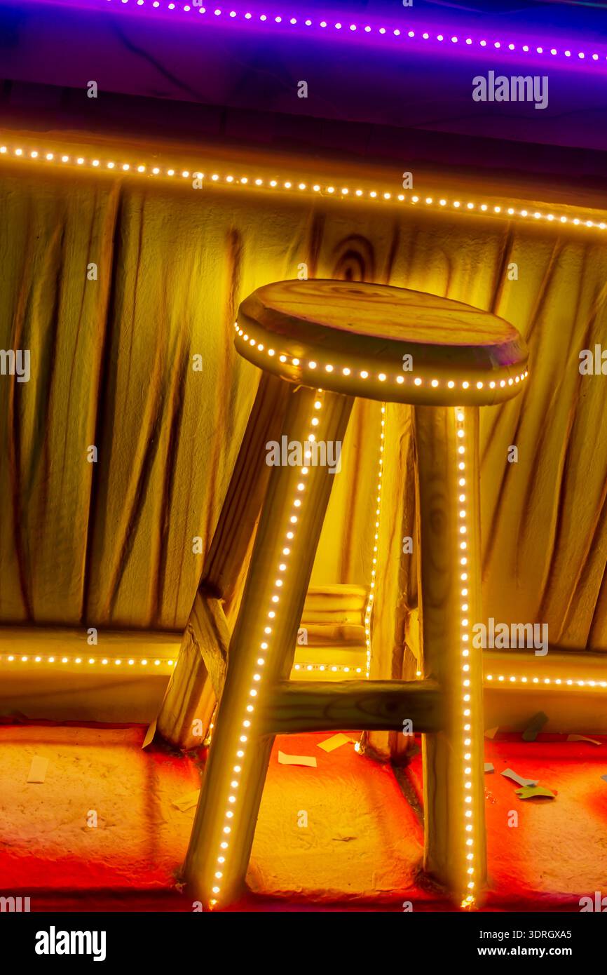 Sgabello da bar in legno con illuminazione a strisce LED e atmosfera al neon con interni in giallo caldo Foto Stock