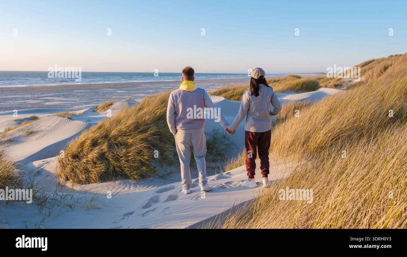 Le coppie passeggiano lungo la splendida spiaggia danese mentre il sole tramonta in una serena serata Foto Stock
