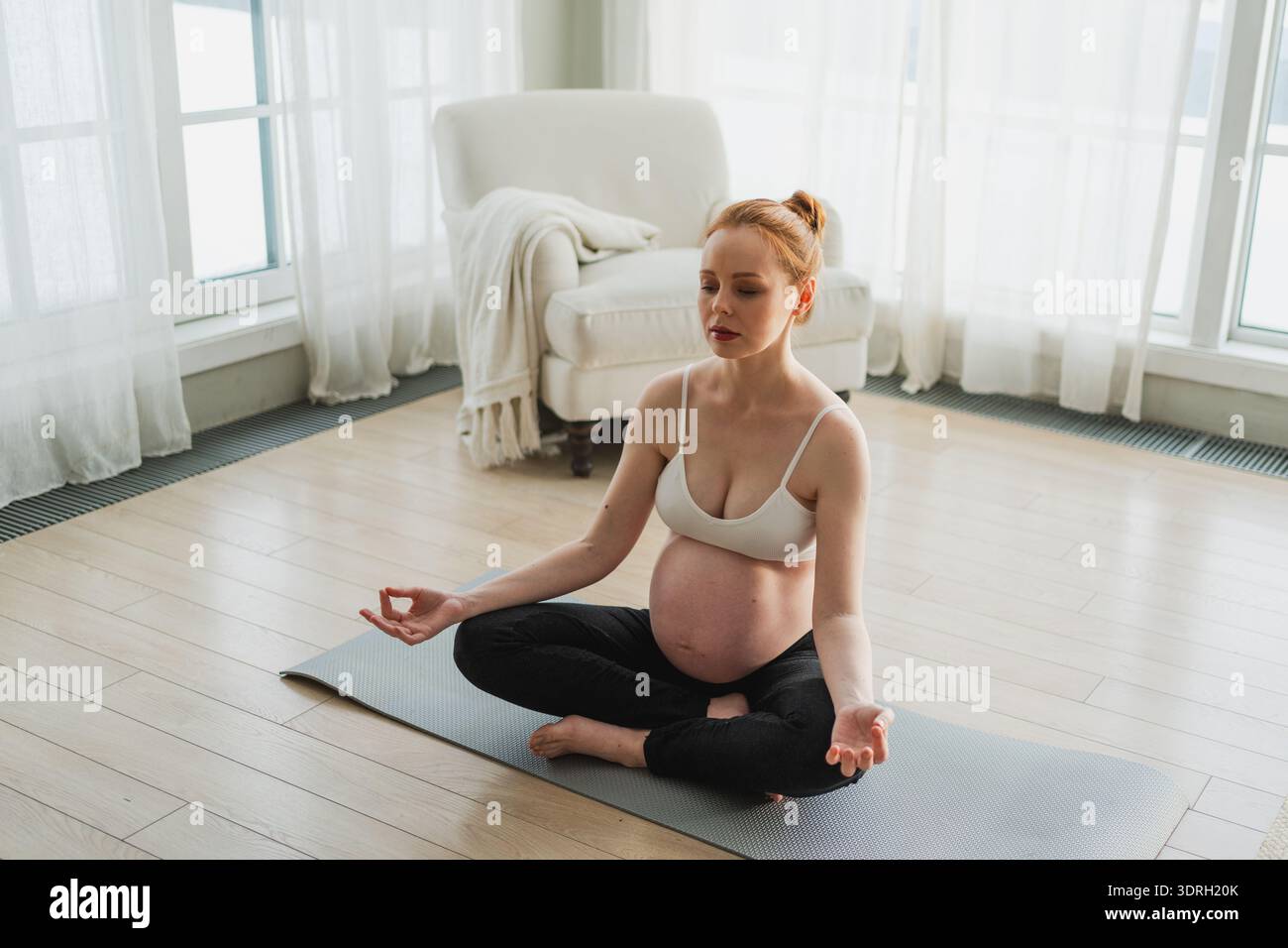 Gravidanza respirazione prenatale. Donna incinta con la pancia grande seduta in posa di loto su yoga opaco a casa. Ragazza incinta che si pratica Foto Stock