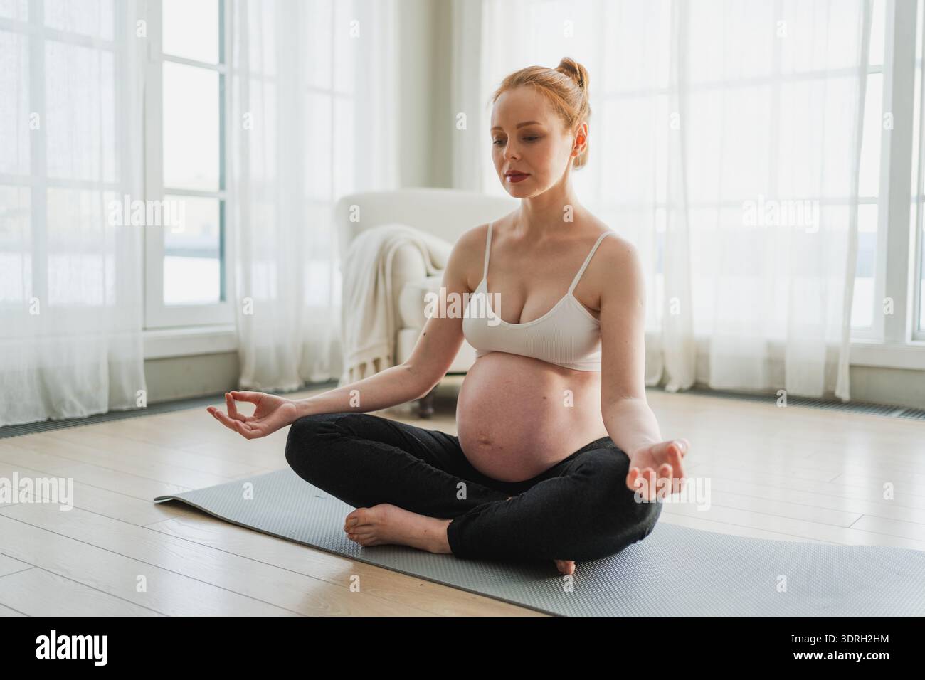 Gravidanza respirazione prenatale. Donna incinta con la pancia grande seduta in posa di loto su yoga opaco a casa. Ragazza incinta che si pratica Foto Stock