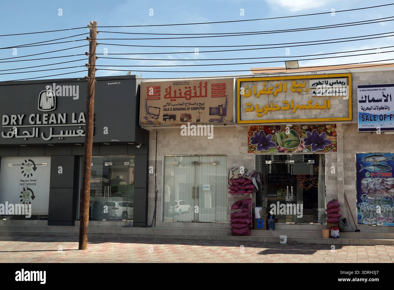 Parata di negozi con pulitori a secco e negozio di riparazione computer vicino al Sultanato Sur di Oman Foto Stock