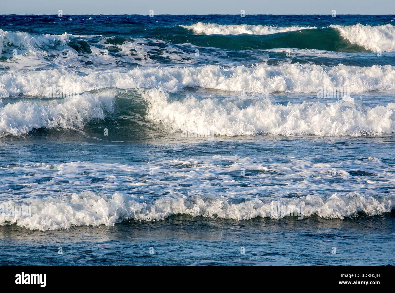 Onde alte si infrangono sulla spiaggia e lentamente si esauriscono. Foto Stock