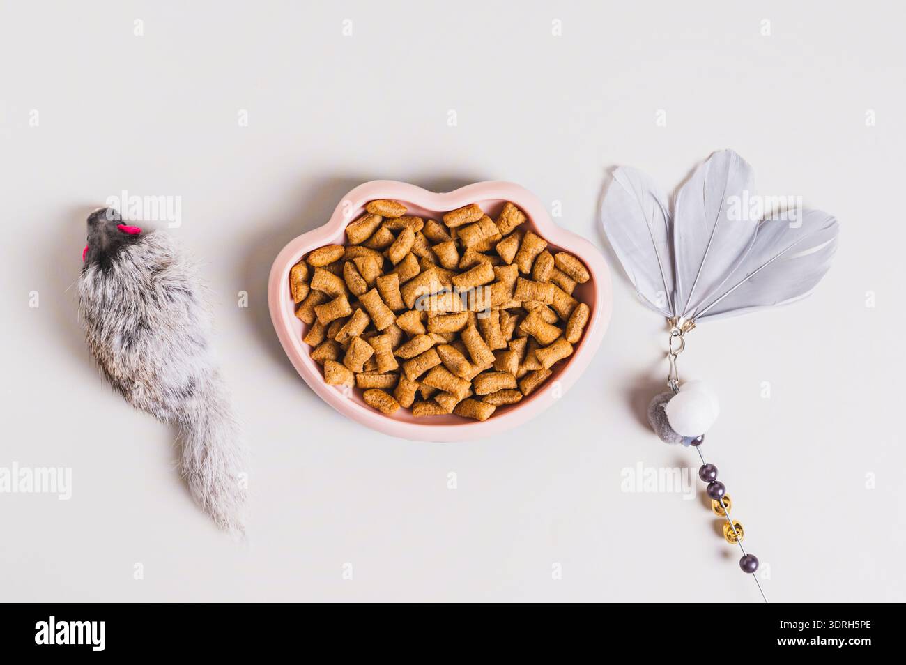 Ciotola con cibo secco per gatti e giocattoli sul tavolo Foto Stock