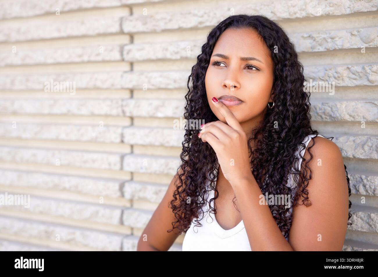 Donna urbana trasuda fiducia nella leadership. La signora contemplativa si rilassa sullo sfondo di mattoni Foto Stock