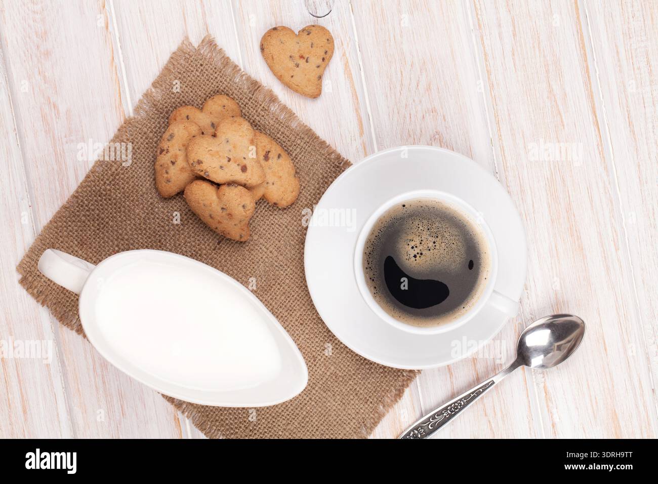 Tazza di caffè, biscotti a forma di cuore e caraffa di latte Foto Stock