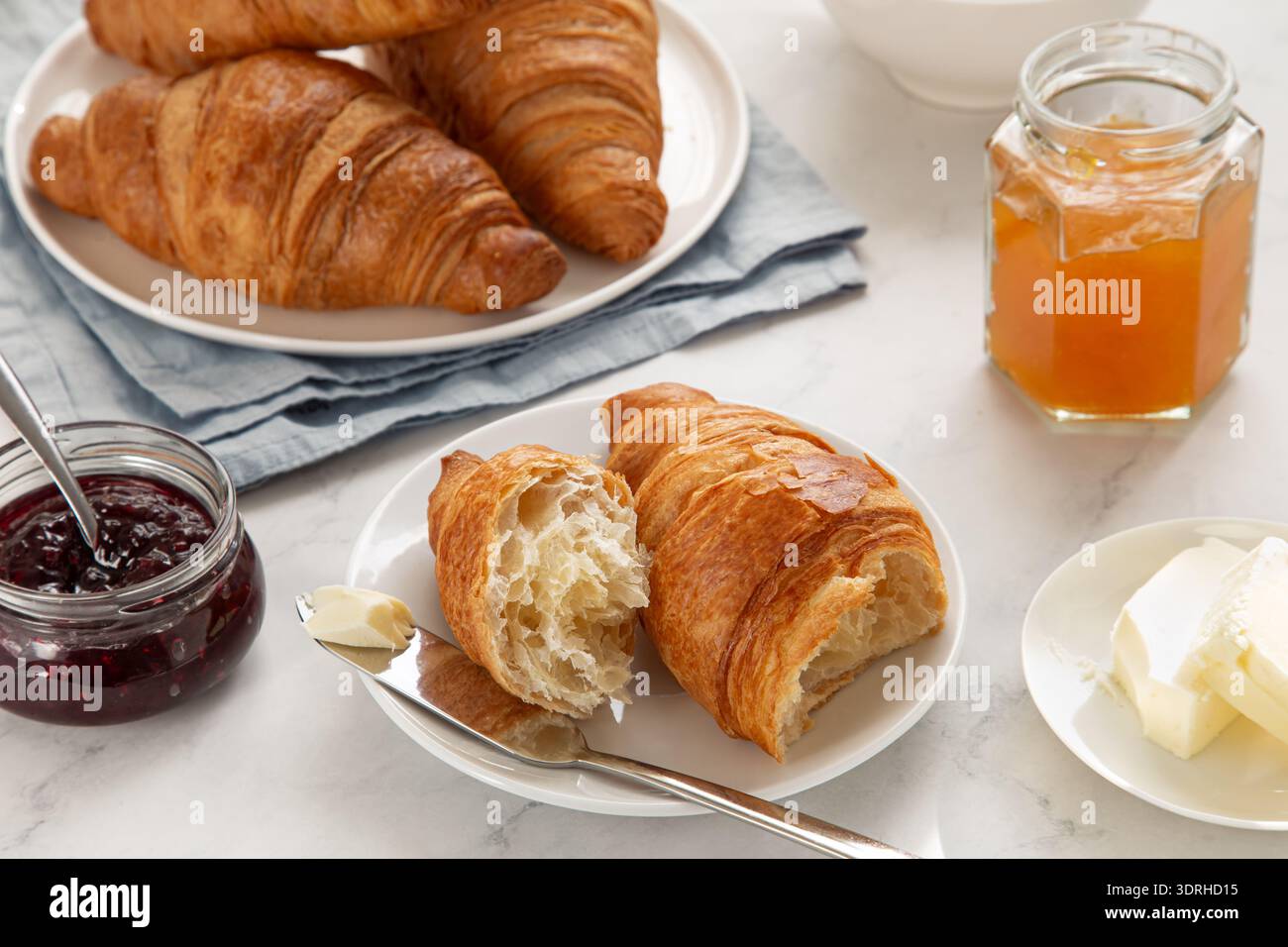 Croissant appena sfornati per colazione, serviti con frutta e marmellata e burro Foto Stock