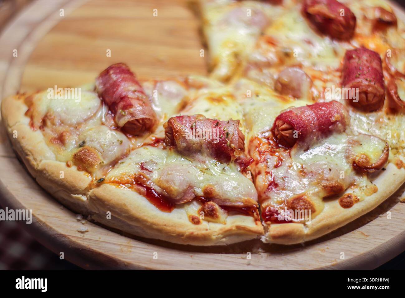 Primo piano, mini salsiccia e pizza con prosciutto e mozzarella sciolta su crosta croccante. Foto Stock