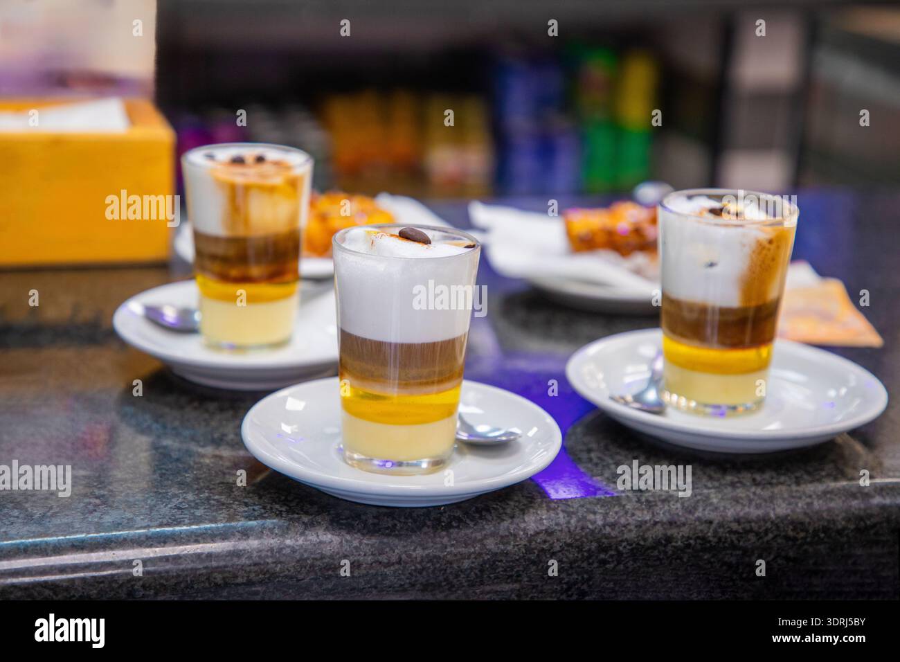Tre bicchieri da dessert a strati con consistenze cremose e sapori ricchi su un piano di lavoro scuro Foto Stock
