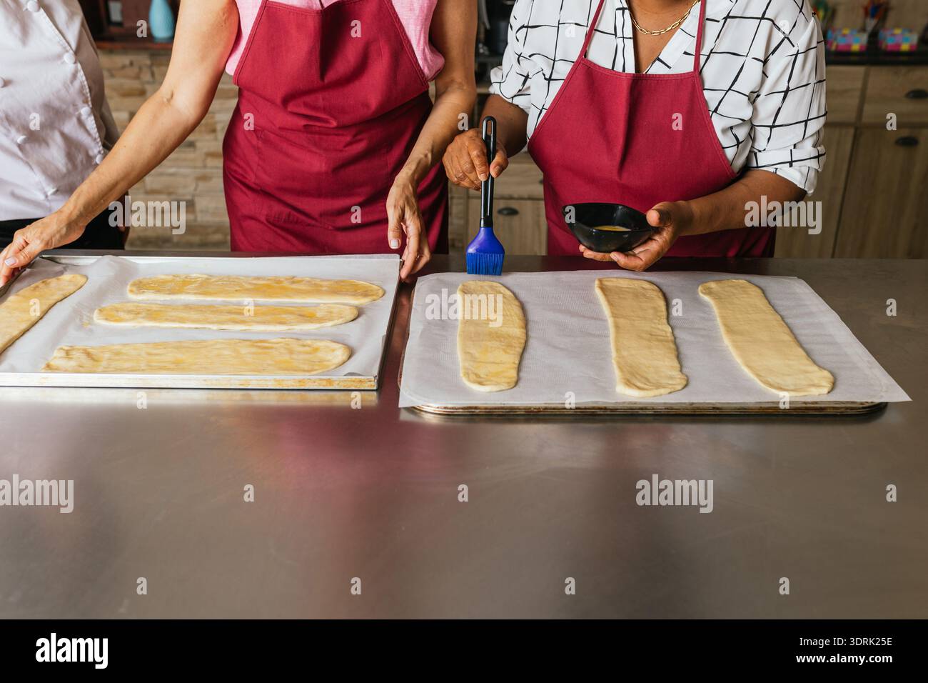 I forni spazzolano l'impasto con il lavaggio delle uova durante la lezione di cucina Foto Stock