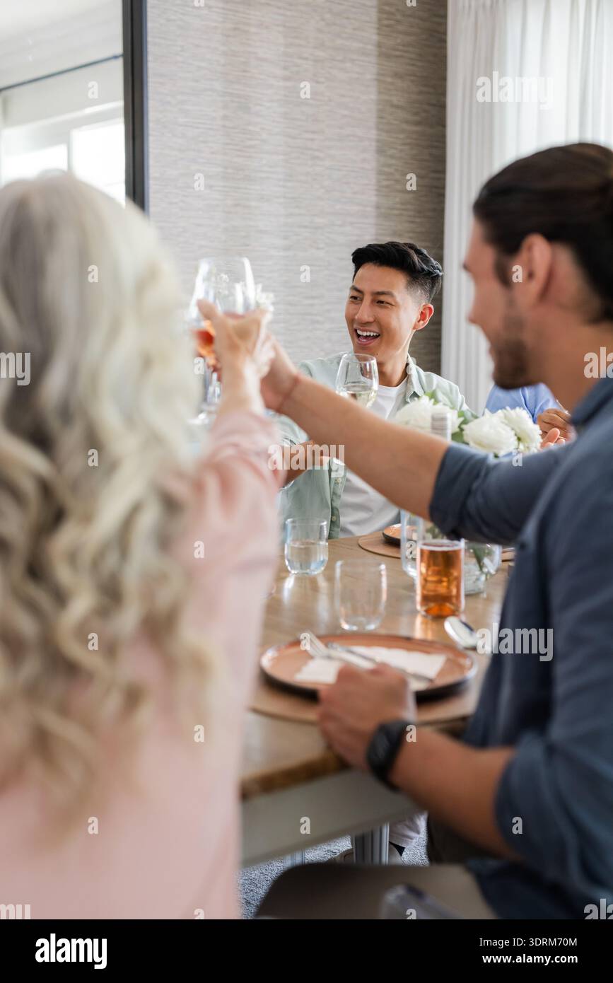 Gli amici brindano con un drink al ricevimento di nozze, festeggiando con gioia e risate. Festeggiamenti, amicizia, gioia, riunione Foto Stock