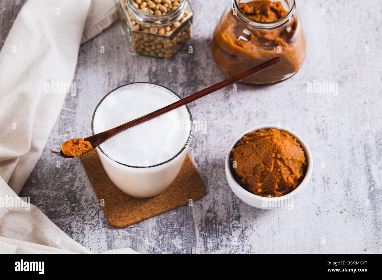 Latte con aggiunta di miso in un bicchiere e una ciotola di pasta di miso sul tavolo Foto Stock