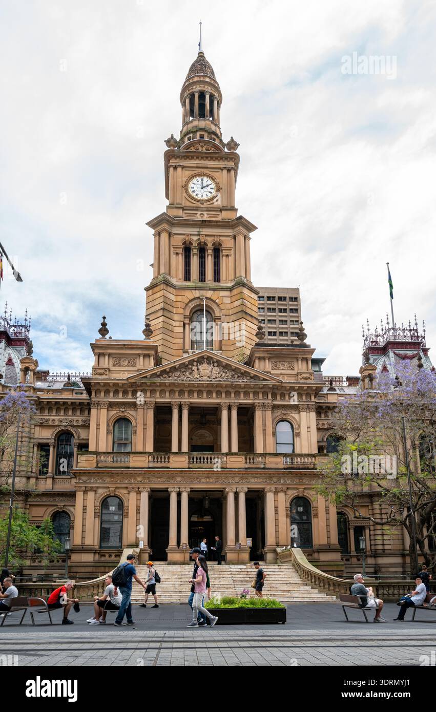 La storica facciata in pietra arenaria e la torre dell'orologio del Municipio di Sydney in George Street durante la stagione primaverile di Jacaranda. Foto Stock