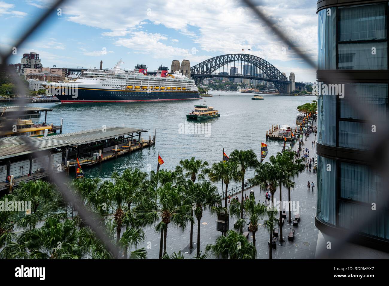 Una veduta sopraelevata della nave da crociera Disney Wonder nel porto di Sydney, incorniciata da una recinzione perimetrale. Foto Stock