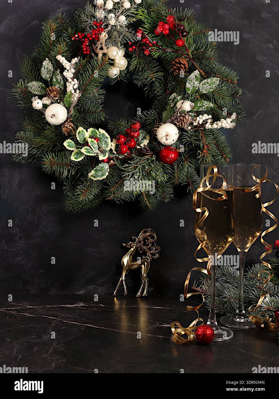 Champagne, decorazioni natalizie e una corona di abete con una statuetta di cervo su uno sfondo elegante, concetto della vigilia di Natale. Anno nuovo" Foto Stock