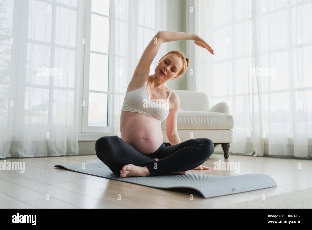 Allenamento fitness yoga gravidanza. Donna incinta che pratica yoga a casa. Ragazza incinta che fa esercizio sportivo sul tappetino da yoga Foto Stock