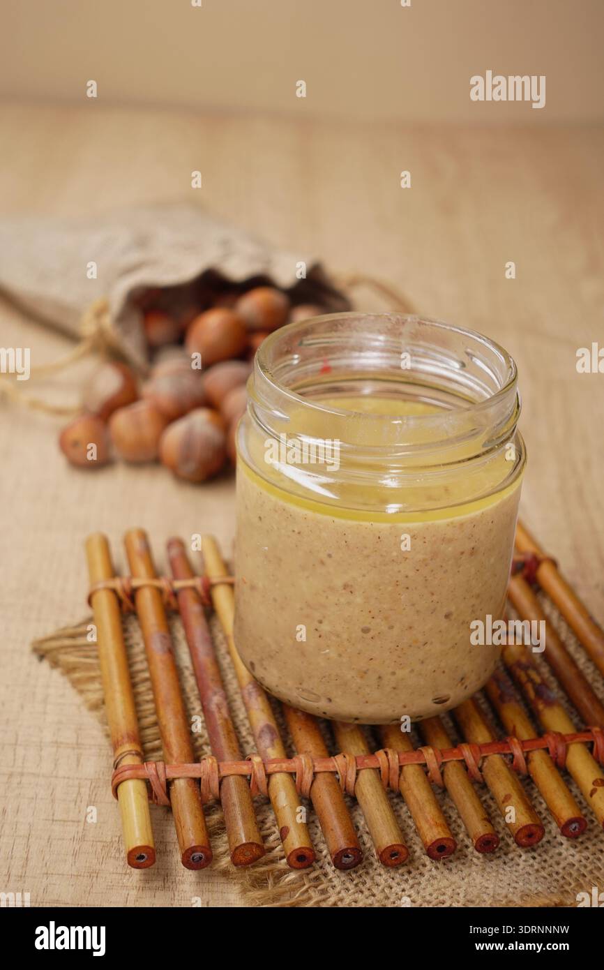 Crema di nocciole in vaso di vetro con colazione Rustic Nocciole intere Foto Stock