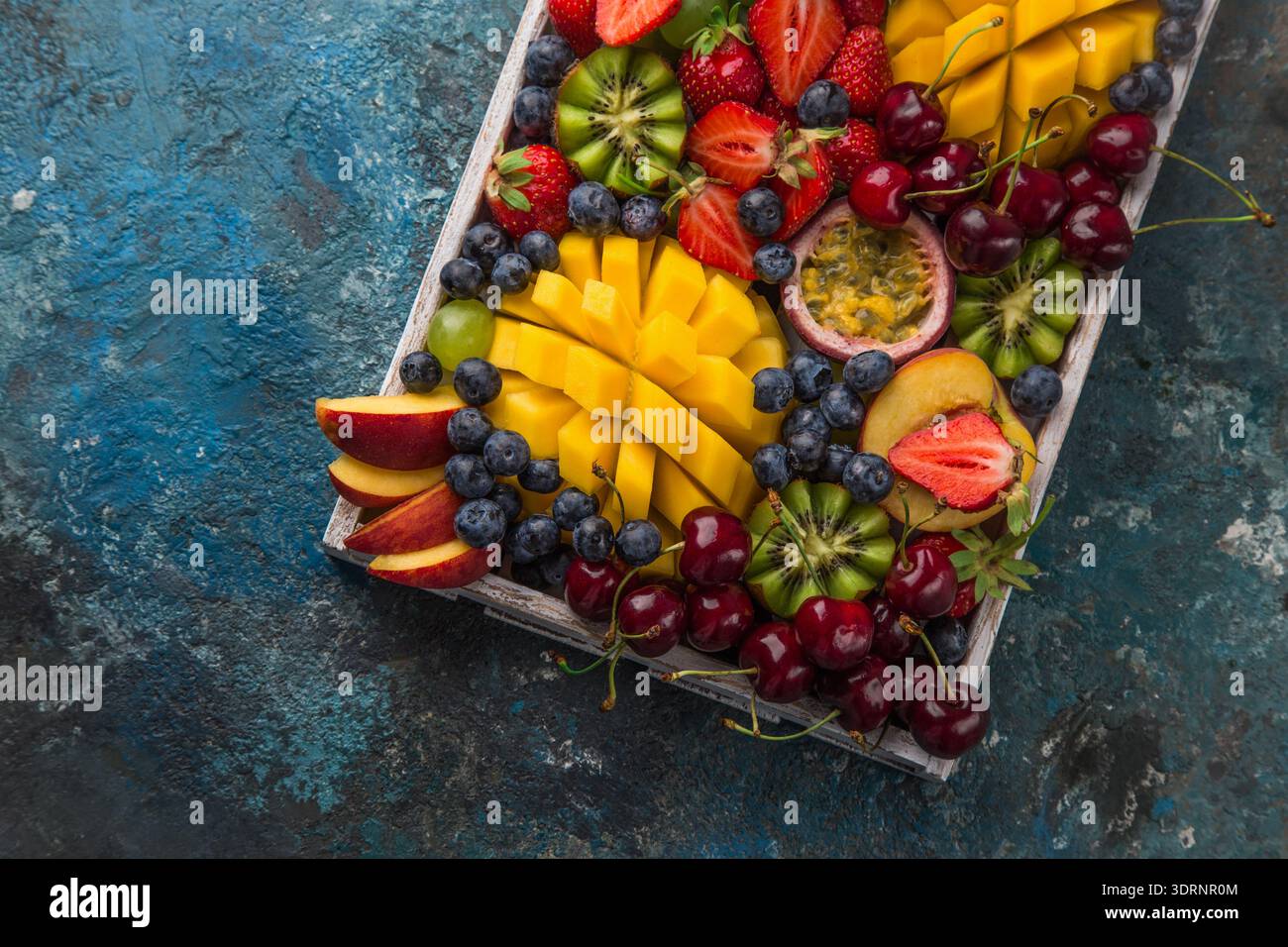 Vassoio di frutta e frutti di bosco deliziosi. Mango, kiwi, fragola, uva, ciliegia, mirtillo, pesca e frutto della passione Foto Stock