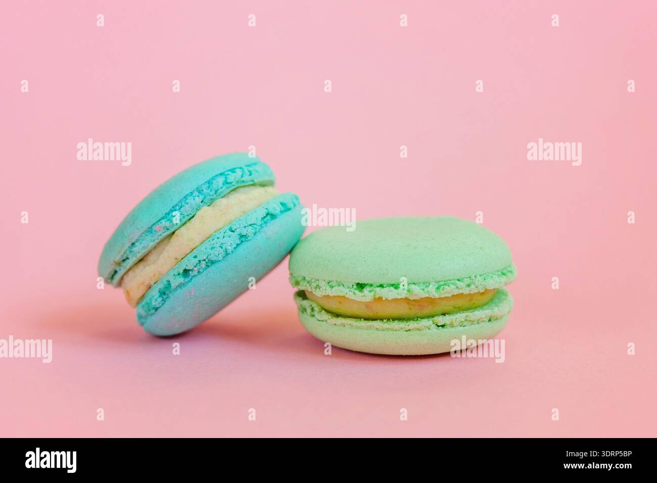 Macaron blu e verde su sfondo rosa Foto Stock