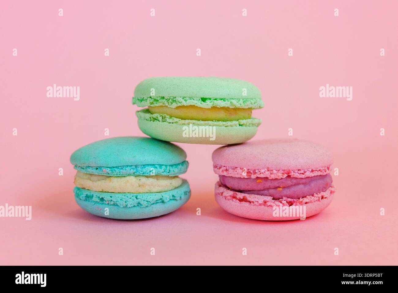 Macaron blu rosa e verde su sfondo rosa Foto Stock