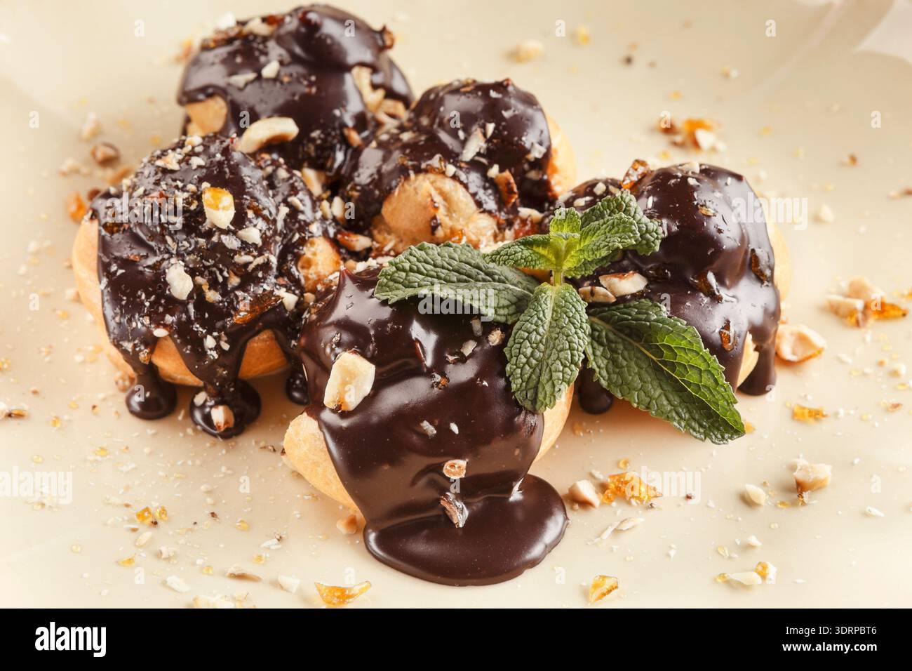 Delizioso dessert con salsa al cioccolato e menta su un piatto ripieno di noci e biscotti tritati Foto Stock