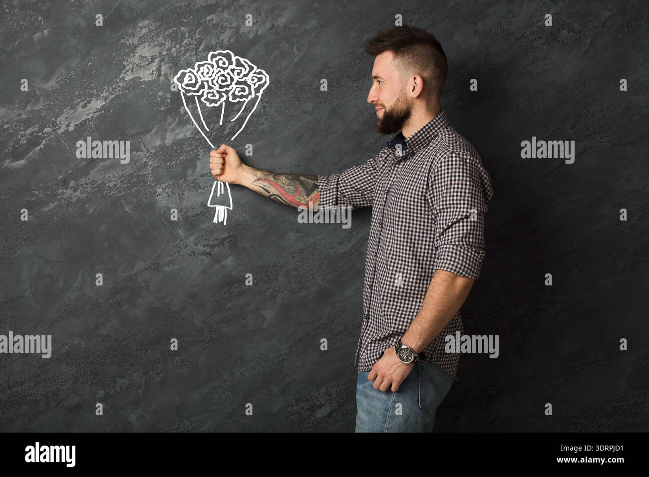 L'uomo tiene un disegno di fiori su una parete in uno studio durante il giorno Foto Stock