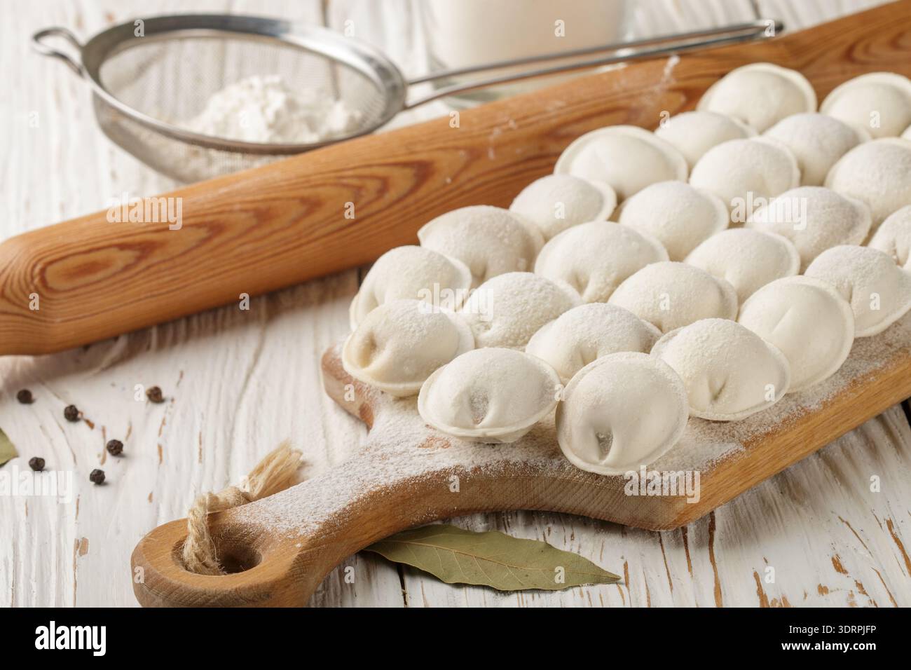 Processo di preparazione di gnocchi di pasta cruda fatti in casa con ripieno di carne su un bordo di legno. Pelmeni. Un piatto tradizionale di cuis russi Foto Stock