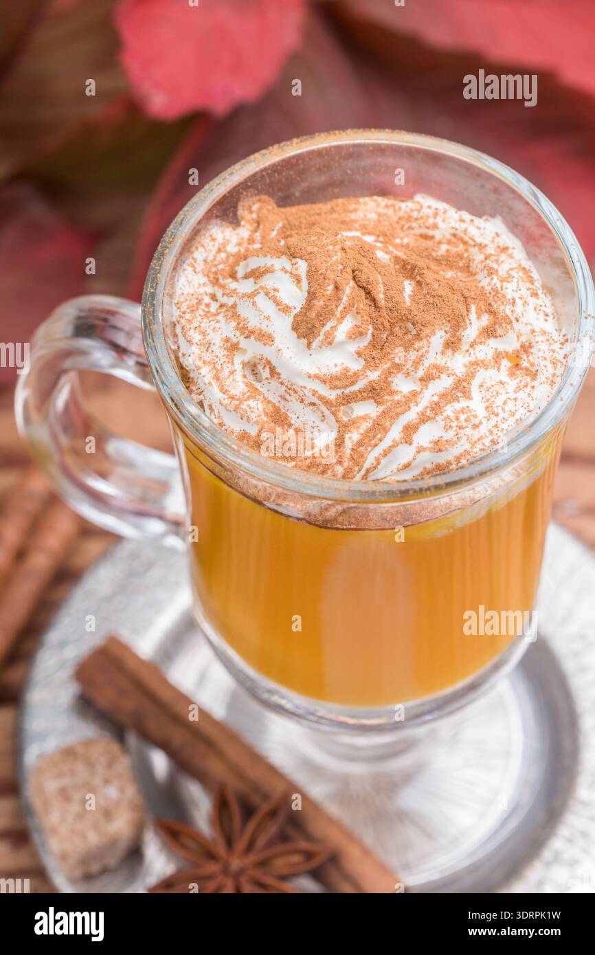 Frullato di latte con spezie di zucca con panna montata e cannella in tazza di vetro su fondo in legno. Tradizionale colazione autunnale calda o fredda Foto Stock