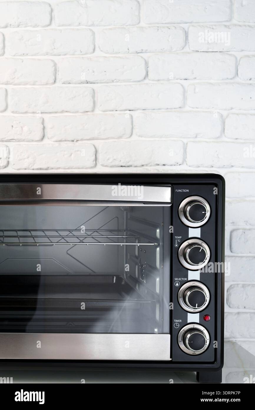 Il moderno forno si trova su un piano cucina vicino a una parete di mattoni bianchi durante le ore diurne Foto Stock