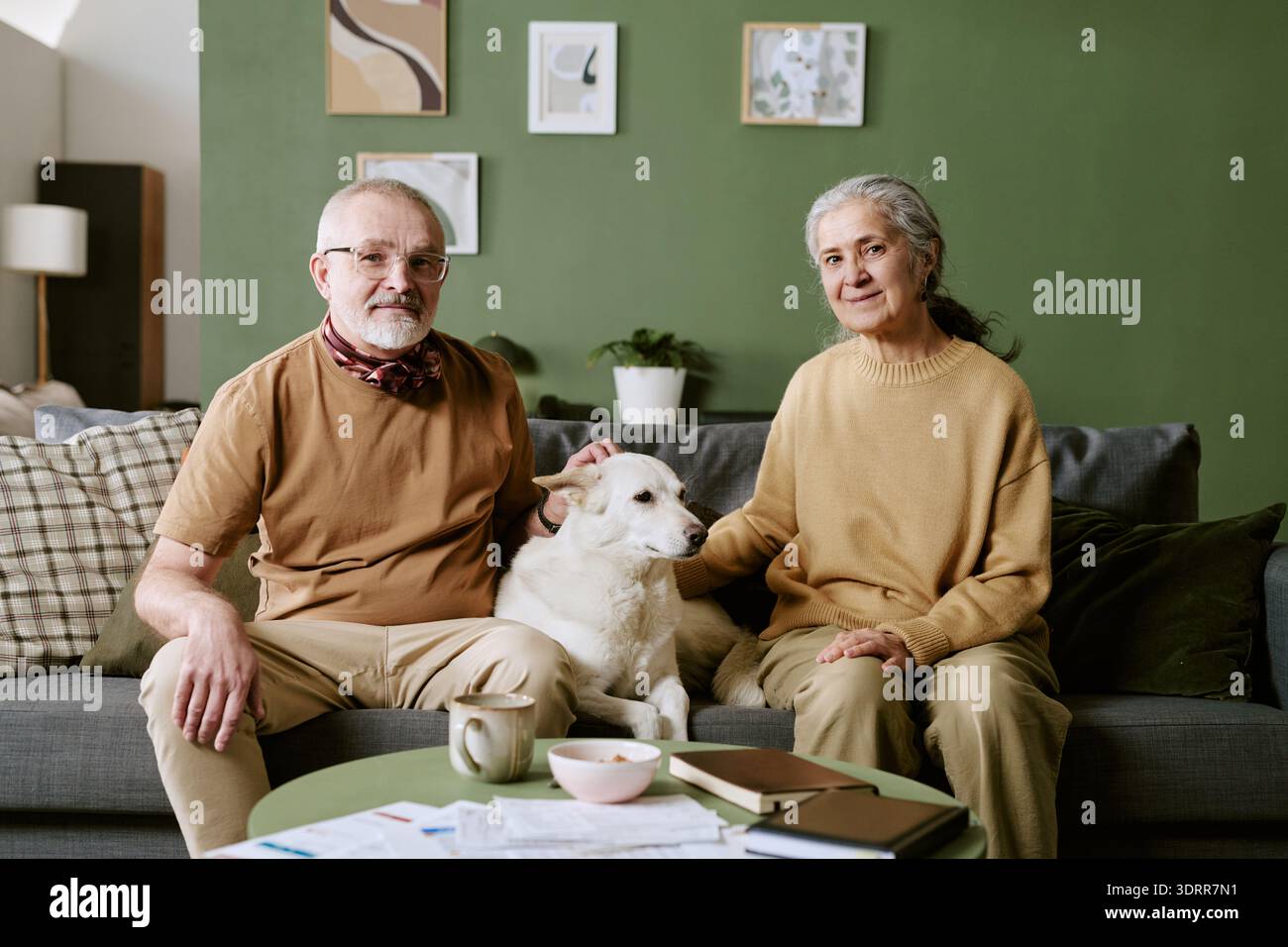 Uomo caucasico anziano e donna caucasica anziana seduta con cane in casa Foto Stock
