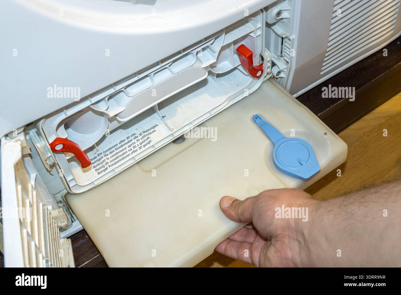 rimuovere a mano il serbatoio dell'acqua dall'asciugatrice per la pulizia Foto Stock