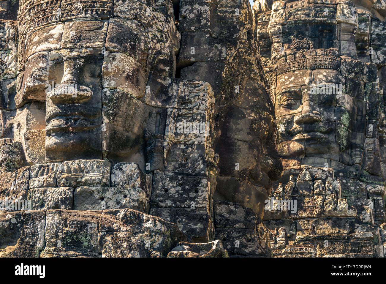 Primo piano di tre gigantesche facce in pietra al tempio Bayon, vista laterale e frontale ad Angkor, Siem Reap, Cambogia Foto Stock