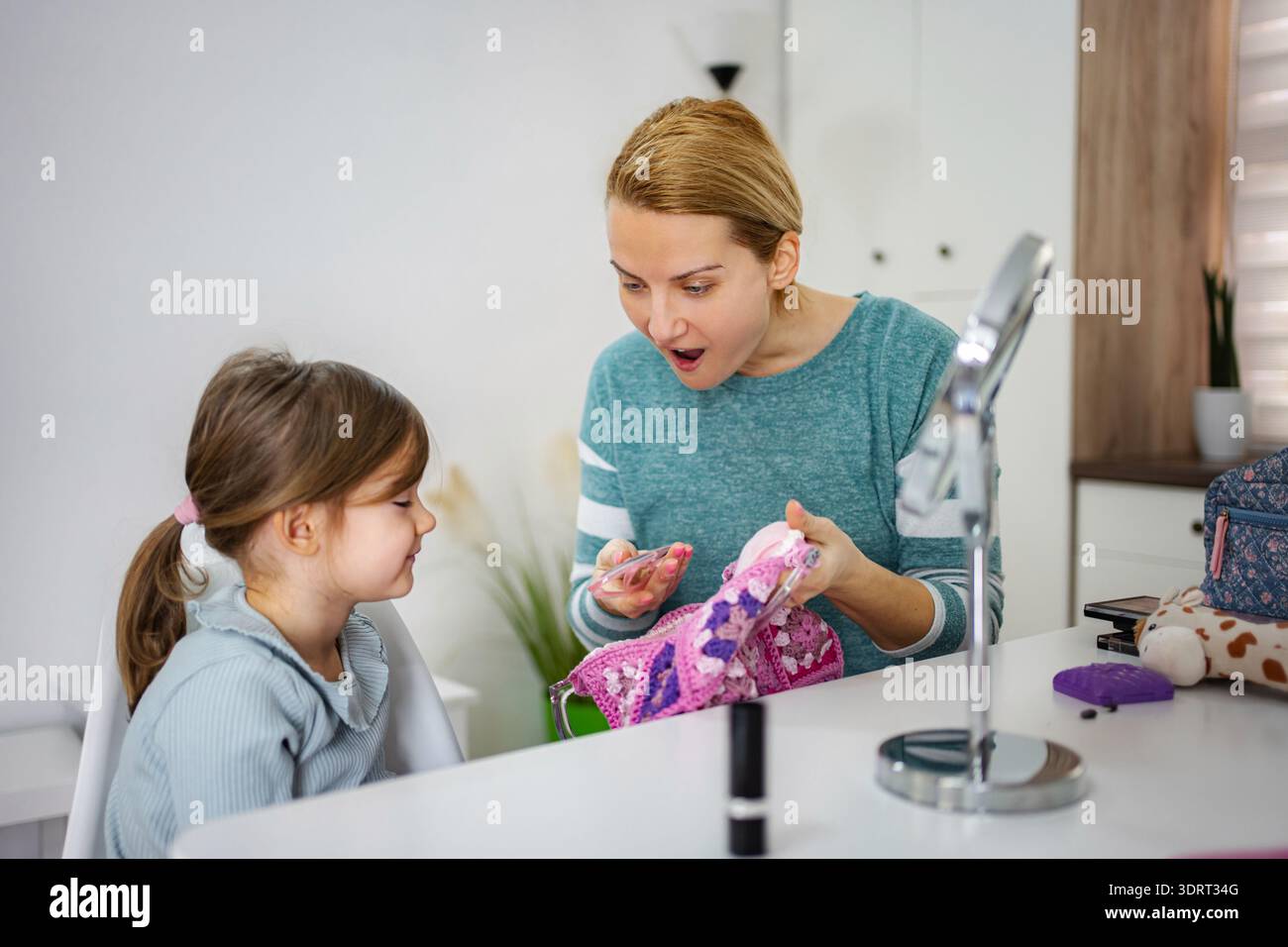Madre e figlia giocano con il trucco, si divertono a casa Foto Stock