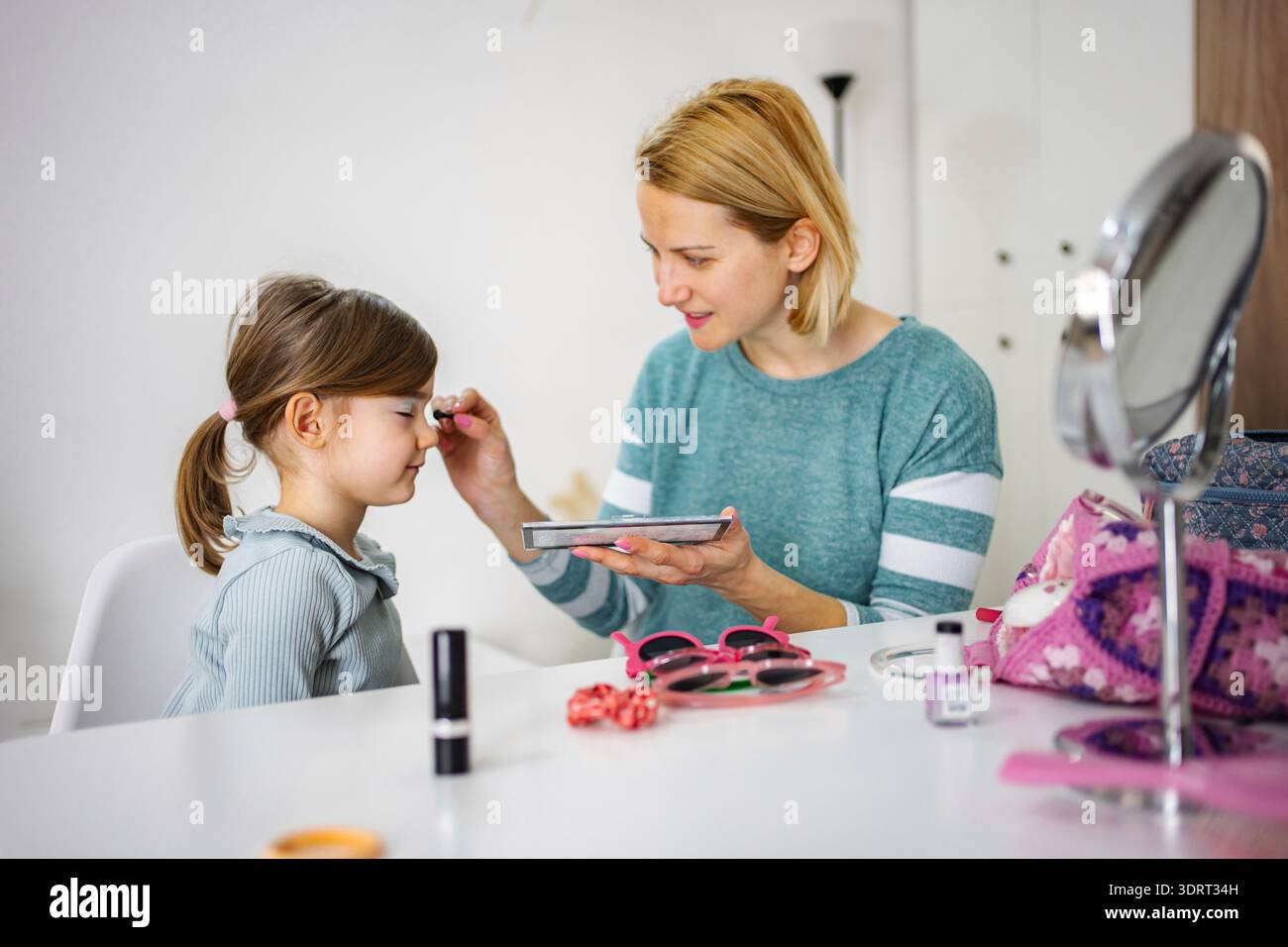 Madre che applica il trucco sugli occhi della figlia a casa Foto Stock